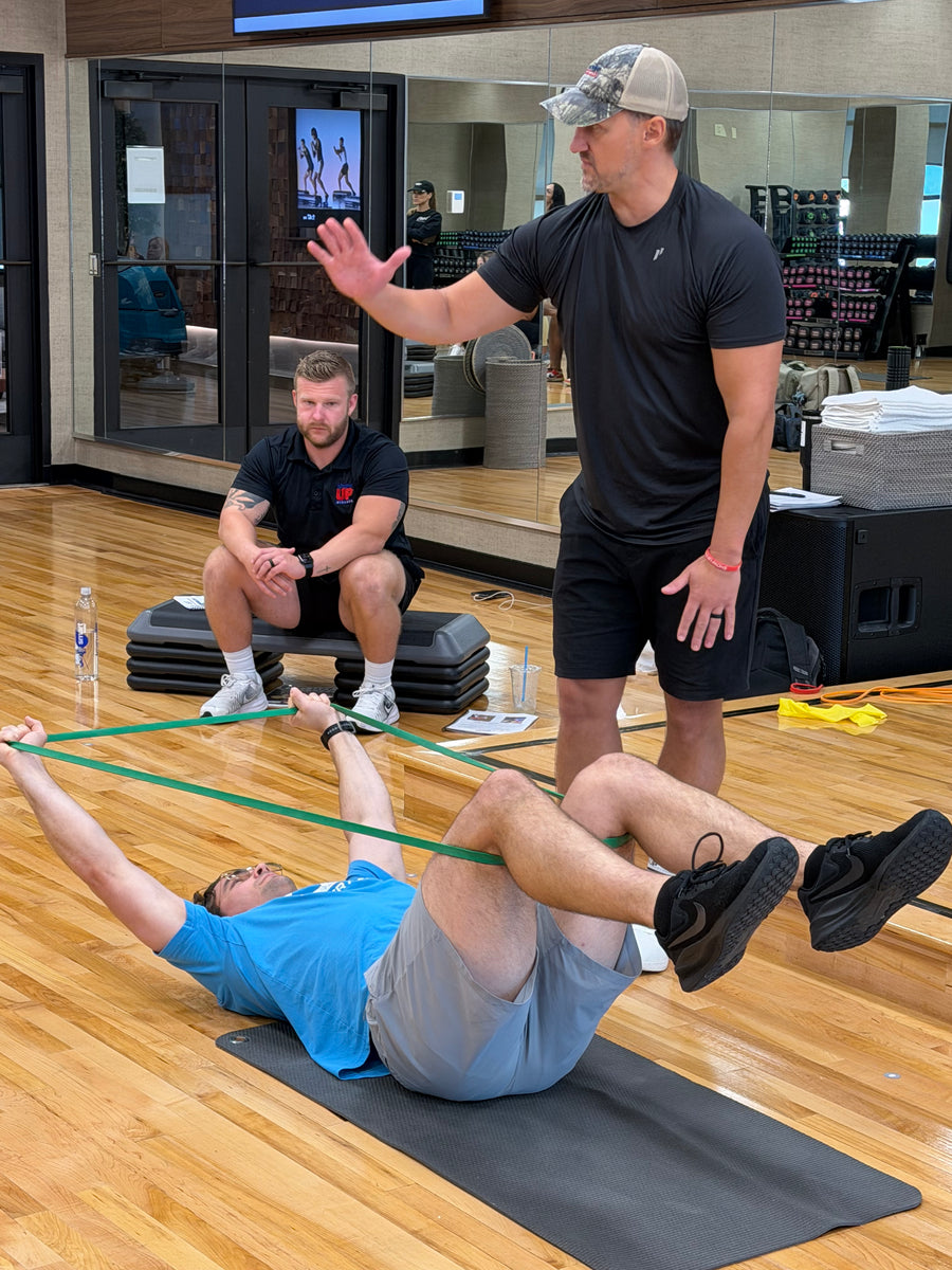 Coaches guiding a client through a hands-on assessment on a mat