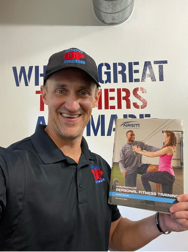 Chris holding an NASM personal training textbook