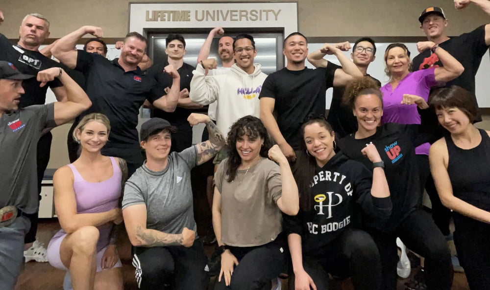 Group of trainees flexing and posing together in front of a Lifetime University sign