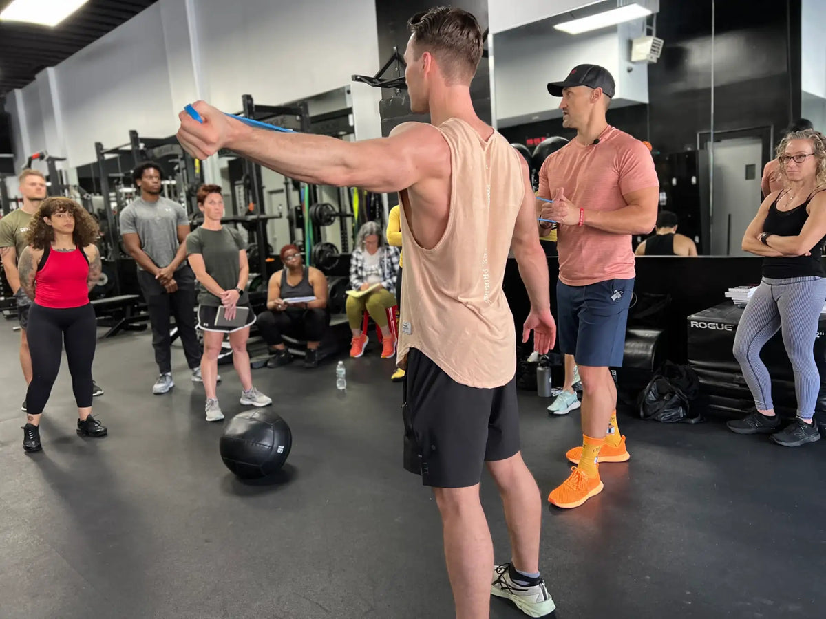Show Up Fitness seminar — coach demonstrating a resistance band exercise