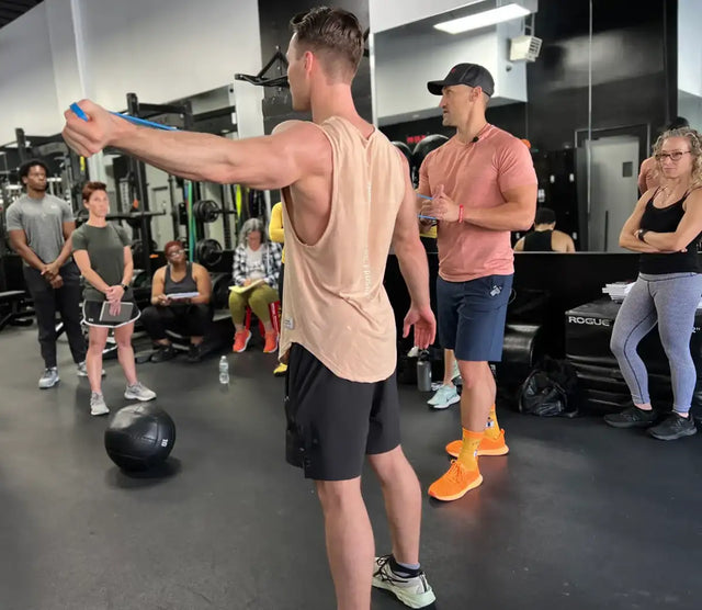Coach demonstrating a resistance band exercise to a trainee