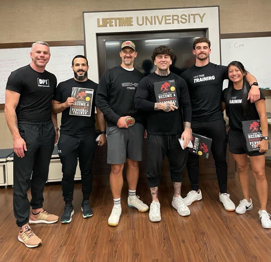 Trainers holding Become a Personal Trainer books in front of a Lifetime University sign